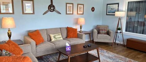 A living room with a sofa, armchairs, a coffee table, and a ceiling fan.