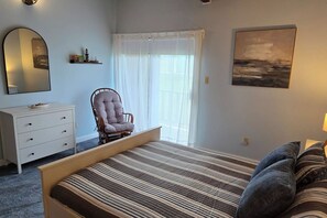A bedroom with a bed, a chair, a dresser, a window with curtains, and a painting on the wall. - Diamond Point~Canal Views! Peaceful with Game Room (Sequim)