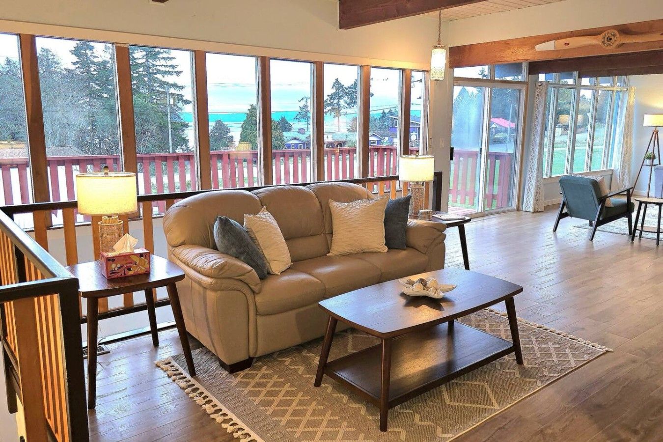 A cozy living room with a sofa, coffee table, and a view of a deck and trees.