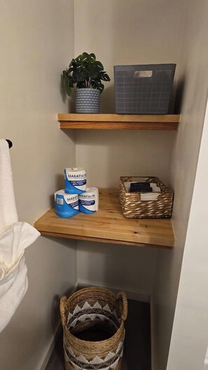 A small bathroom with a wooden shelf holding a plant, a basket, and toilet paper. - Diamond Point~Canal Views! Peaceful with Game Room (Sequim)