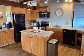 A modern kitchen with wooden cabinets, a black refrigerator, a microwave, an oven, and a dishwasher. - Diamond Point~Canal Views! Peaceful with Game Room (Sequim)