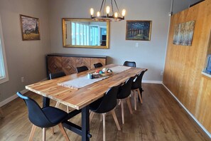 A dining area with a wooden table, black chairs, a bench, and artwork on the walls. - Diamond Point~Canal Views! Peaceful with Game Room (Sequim)