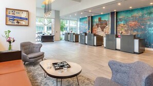 A spacious lobby with a reception desk, seating area, and a large abstract mural. - Resort Condo near SXSW (Austin)