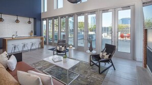A spacious living area with a modern kitchen, large windows, and a balcony with outdoor seating. - Resort Condo near SXSW (Austin)