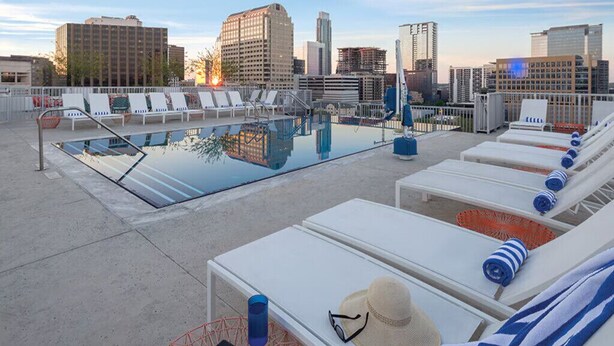 A rooftop pool area with lounge chairs and a cityscape view. - Resort Condo near SXSW (Austin)
