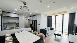 A modern hotel room with a kitchen, dining area, and a balcony with a city view. - HN ETH Vinhomes Skylake Resident (Hanoi)