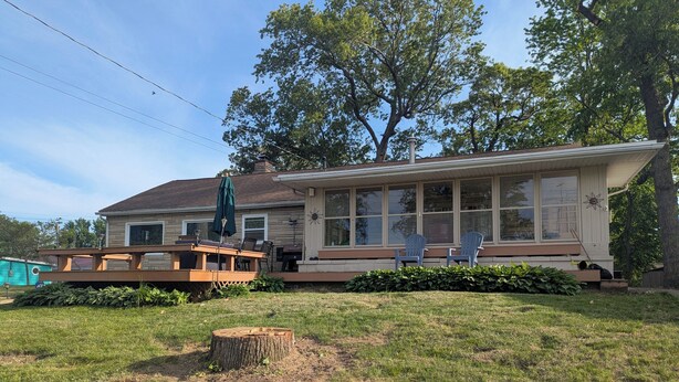 A house with a covered patio, outdoor seating, and a large window overlooking the yard. - Cozy Ranch Retreat! Peace, Lake Views, Game Room & Hot Tub (Knox)