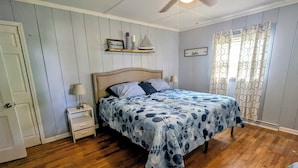 A bedroom with a bed, a nightstand, a ceiling fan, and a window with patterned curtains. - Cozy Ranch Retreat! Peace, Lake Views, Game Room & Hot Tub (Knox)