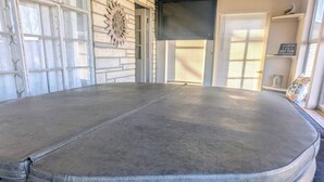 A spa tub in a room with a stone wall, a sun decoration, and a sign on the wall. - Cozy Ranch Retreat! Peace, Lake Views, Game Room & Hot Tub (Knox)