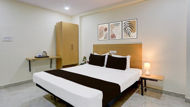 Una camera d'albergo con un letto grande, un armadio in legno, un comodino con una lampada e decorazioni alle pareti.