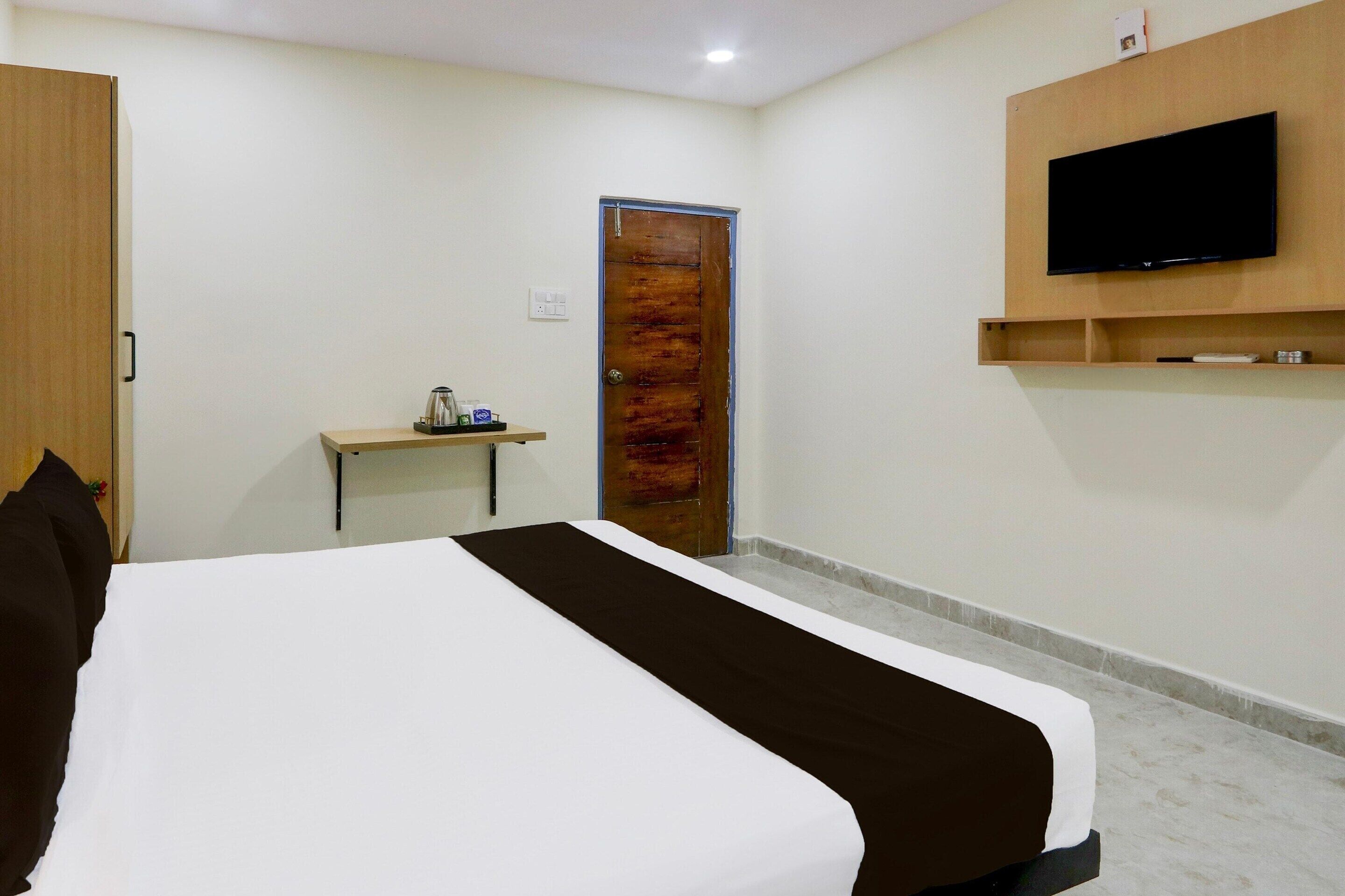 A hotel room with a bed, a desk, a television, and a door.