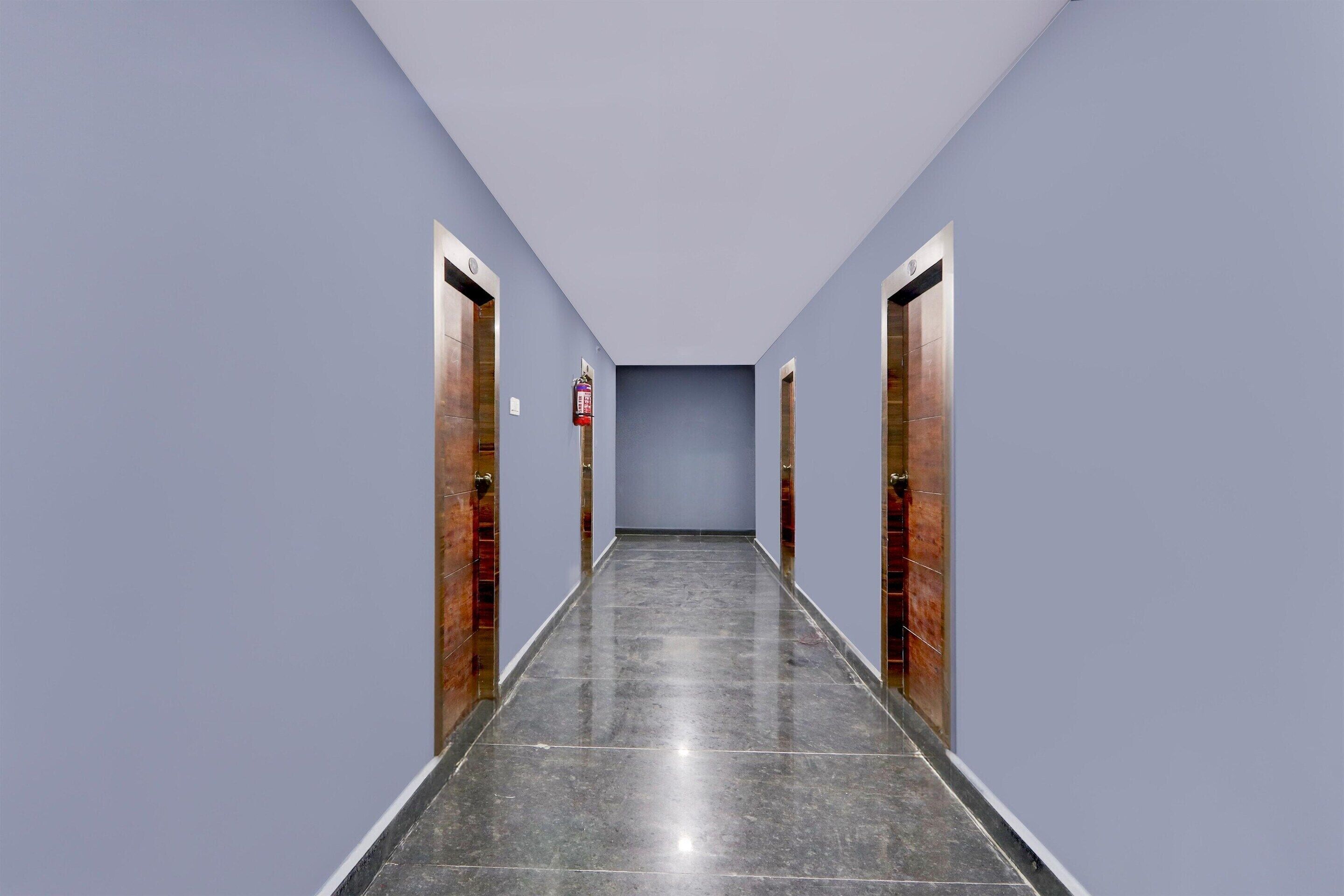 A long, narrow hallway with light blue walls and dark tiled flooring.