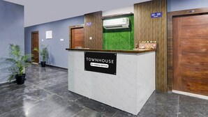 Una reception con la scritta "TOWNHOUSE", un cartello aziendale, un muro di erba sintetica verde e un pannello decorativo in legno.