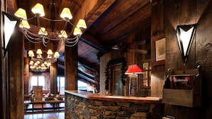A rustic interior with a stone wall, wooden beams, and a chandelier. - Chalet in Paradiski With Stunning Ski Views (Bourg-Saint-Maurice)