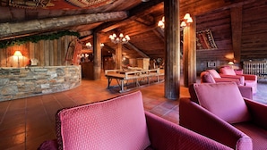 A rustic interior with wooden beams, stone walls, and red upholstered chairs. - Chalet in Paradiski With Stunning Ski Views (Bourg-Saint-Maurice)