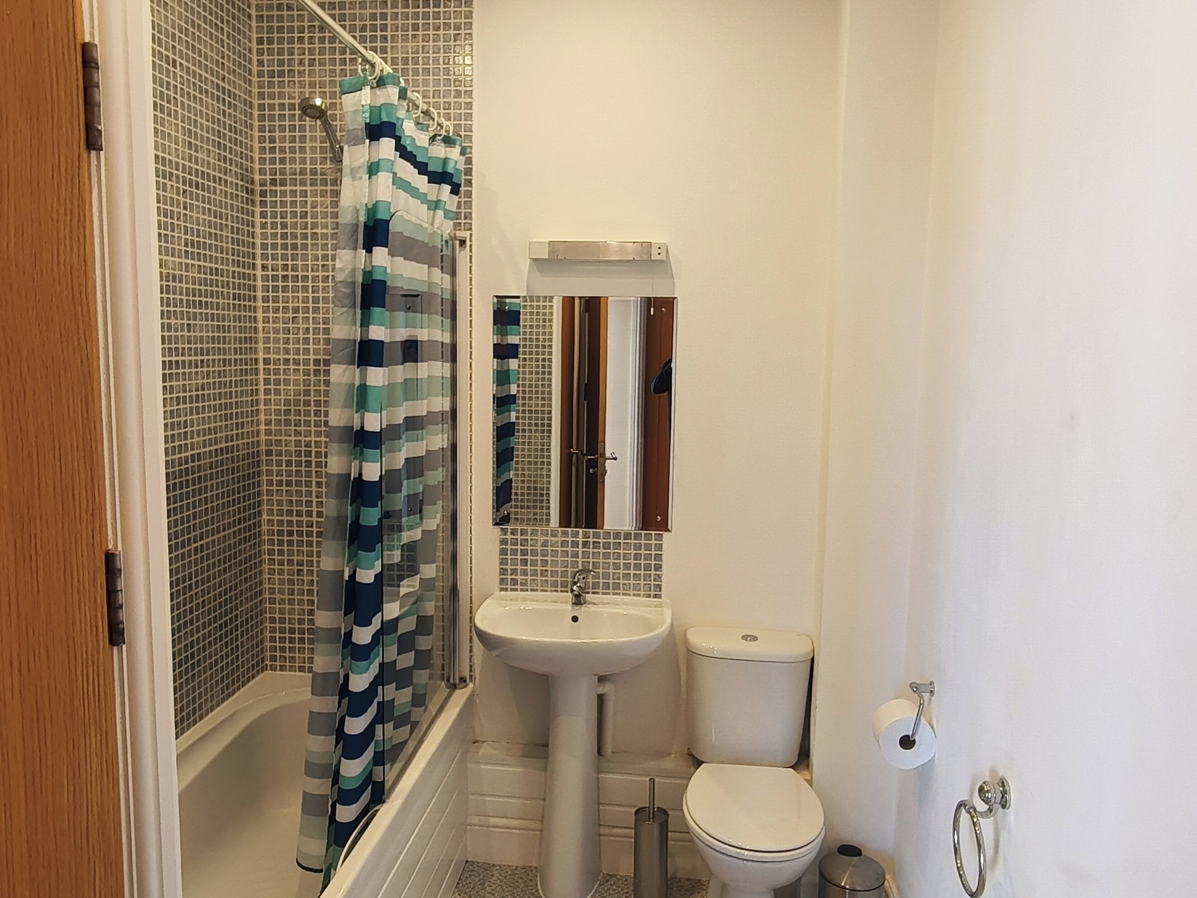 Une salle de bain équipée d’une douche, d’un lavabo, de toilettes et d’un miroir.