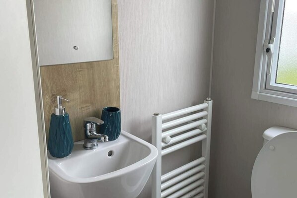 A bathroom with a white sink, a mirror, a towel rack, and a toilet.