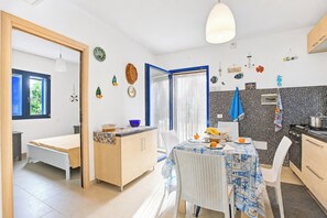 A compact kitchen with a dining area, a small seating space, and a view through a door. - Villetta Pino Pool & Sea w/Terrace, Nardò, Italy (Nardò)