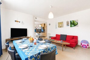 A dining area with a table set for four, a red sofa, and a television in the background. - Villetta Pino Pool & Sea w/Terrace, Nardò, Italy (Nardò)