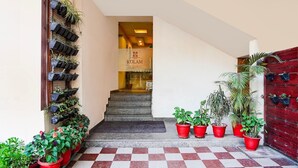 A hotel entrance with a checkered floor, a staircase, and potted plants on either side. - Classic Hotel Kolam (Dehradun)