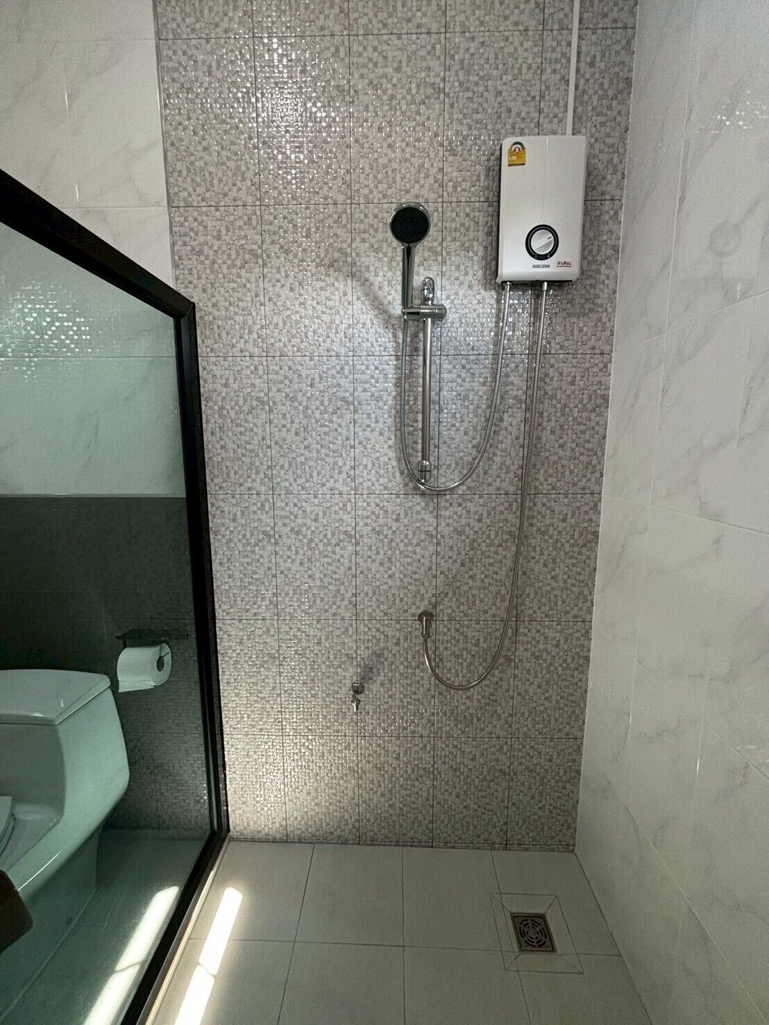 Un baño con ducha, inodoro y separador de vidrio.
