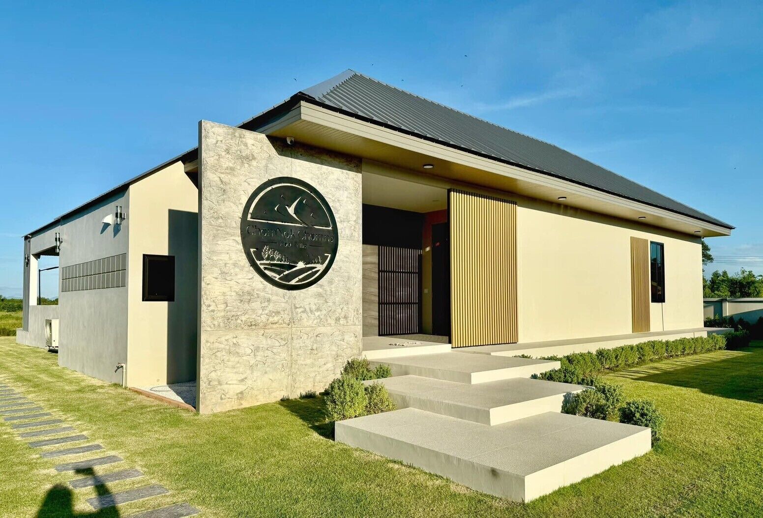 A modern house with a stone facade, a large circular sign, and a well-maintained lawn.