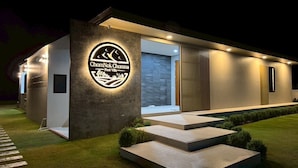 A modern building with a circular logo, a pool, and a well-maintained lawn. - Chomnok Chomna Pool villa (Khlung)