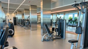 Une salle de sport équipée de divers appareils d’exercice, notamment des tapis de course, des appareils de musculation et un banc.