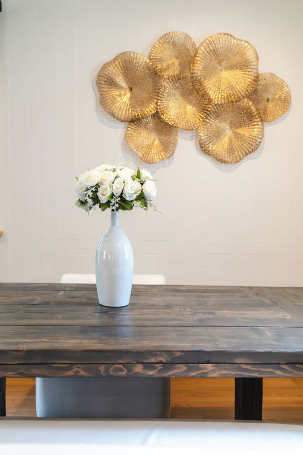 A white vase with white flowers on a wooden table.