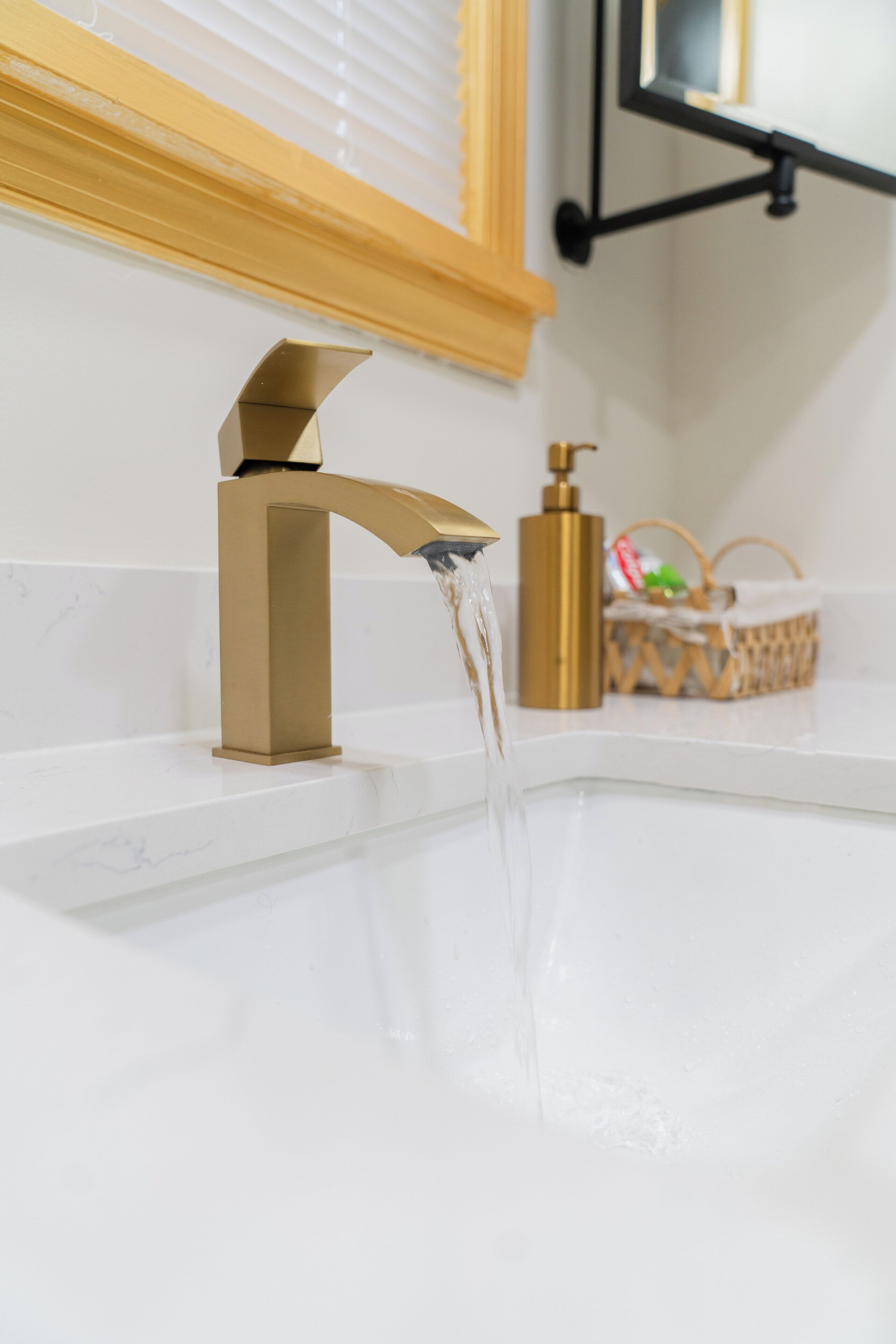 A bathroom with a gold faucet and a white sink.