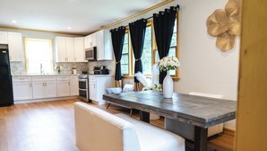 Una cocina moderna con armarios blancos, una mesa de comedor de madera oscura y un banco.