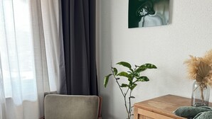 Una stanza con una sedia di legno, una pianta in vaso, un armadietto di legno e un quadro appeso al muro.