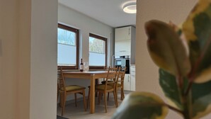Zona pranzo con tavolo, sedie e una bottiglia di vino.