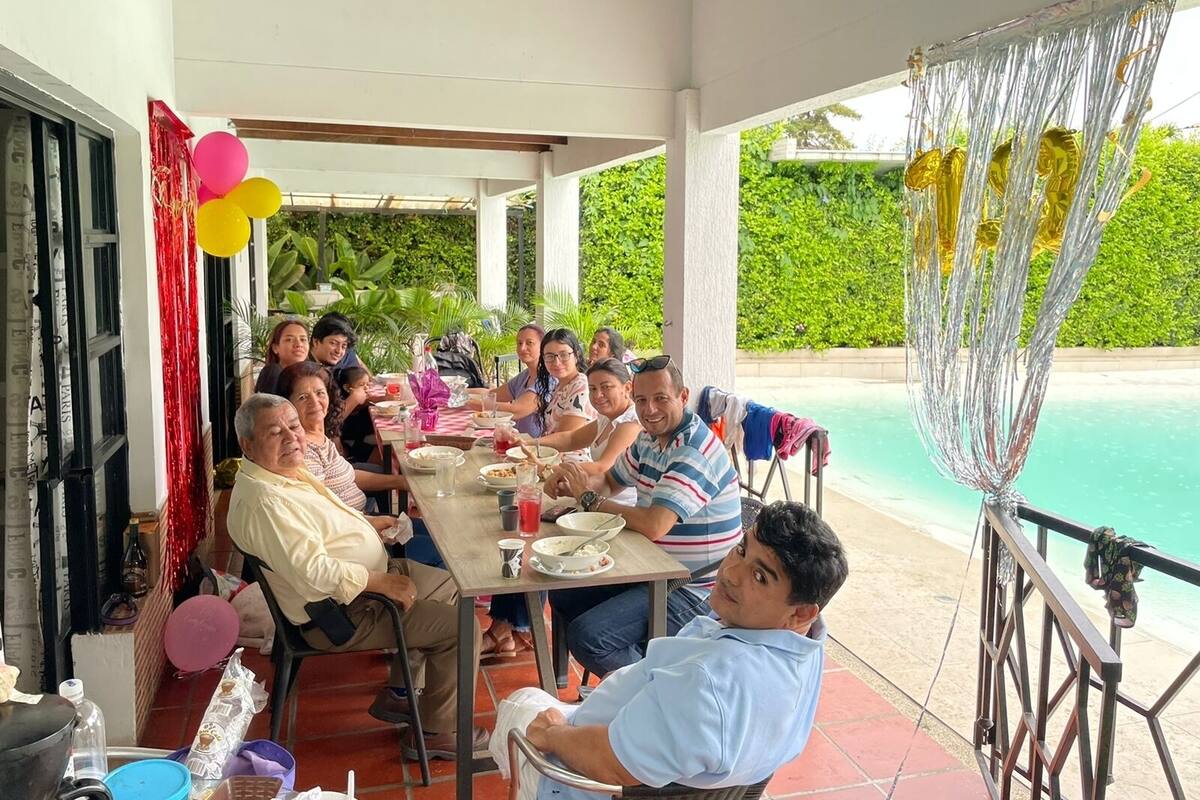 A group of people dining at an outdoor table with a pool view.