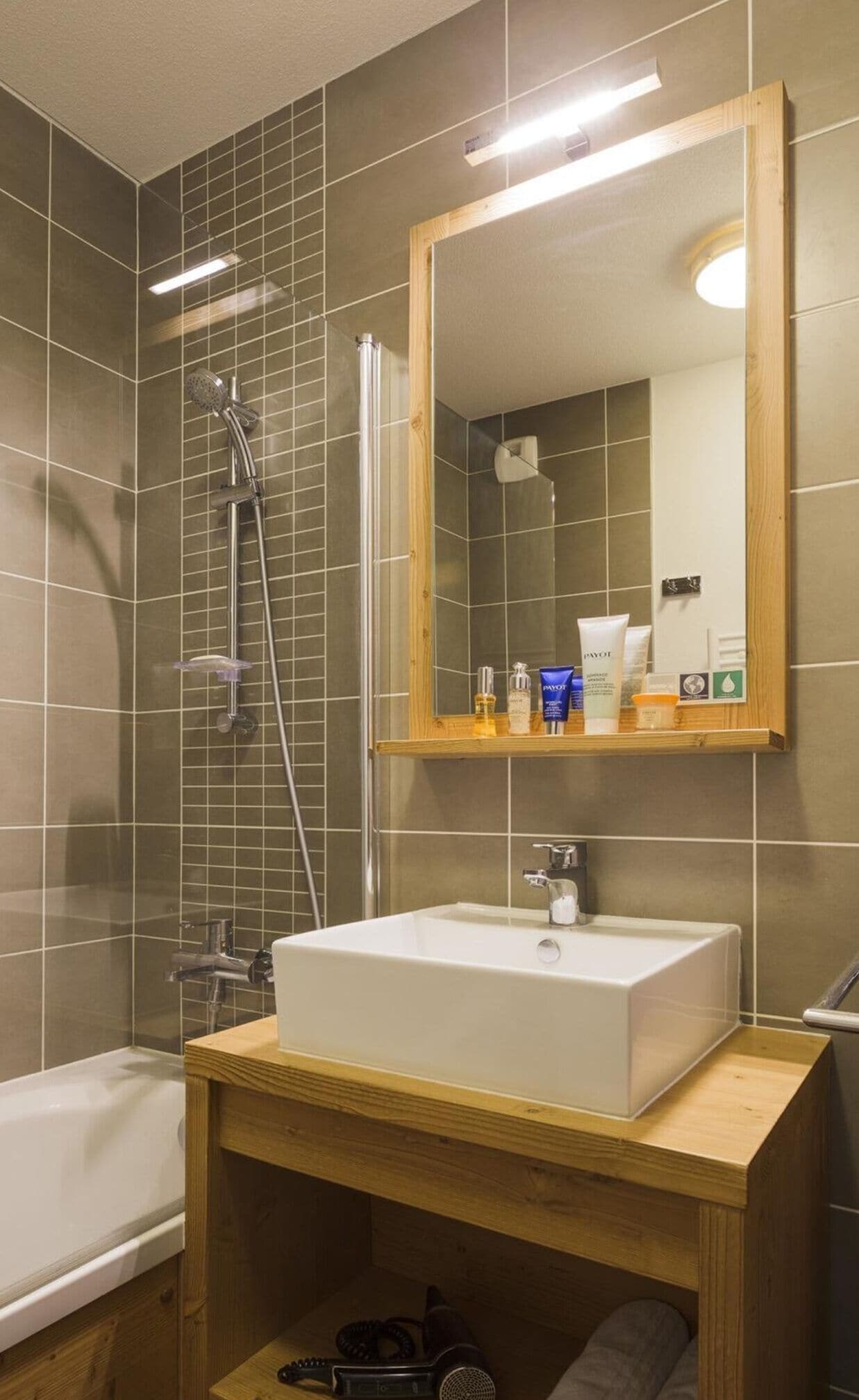 Uma casa de banho moderna com um espelho grande, uma banheira e uma pia.