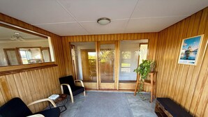 A room with wooden paneling, a large mirror, two black chairs, a small table, a bench, and a potted plant. - Comfort at Stag Lodge Just Mins Walk to Queens Park & Down Town Invercargill (Invercargill)