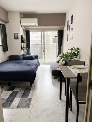 A modern bedroom with a bed, a desk, and a dining area. - Walking to Dotonbori, the heart of Osaka (大阪市)