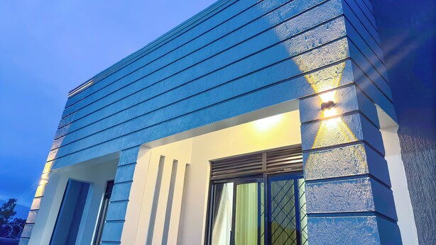 Un bâtiment moderne à la façade bleue et à l’entrée bien éclairée.