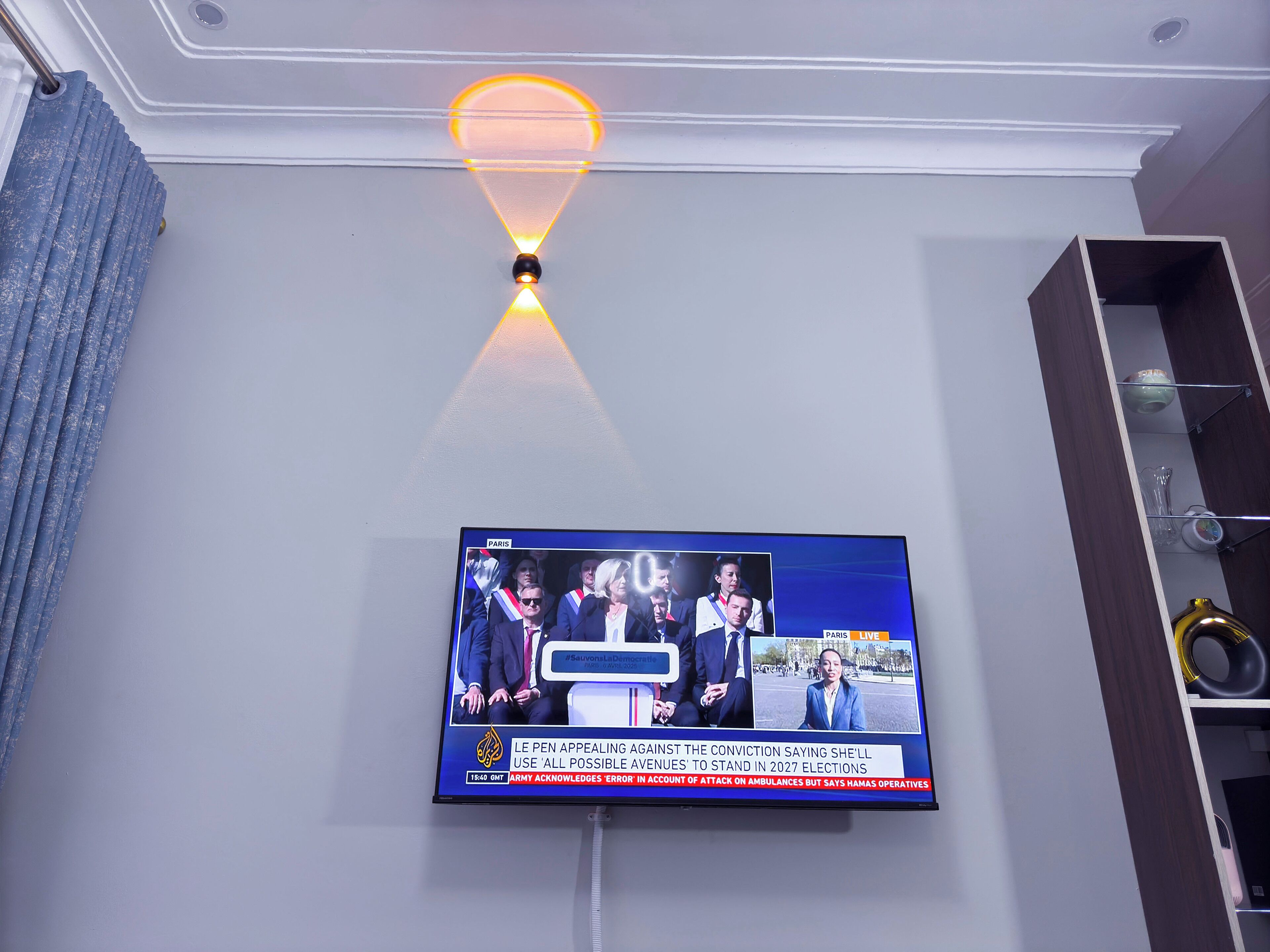 Un téléviseur fixé au mur diffusant un journal télévisé.