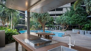 An outdoor pool area with a bar, seating, and a view of the surrounding greenery and buildings.