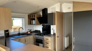 Eine moderne Küche mit Holzausstattung, einem Edelstahlherd und einem schwarzen Kühlschrank.