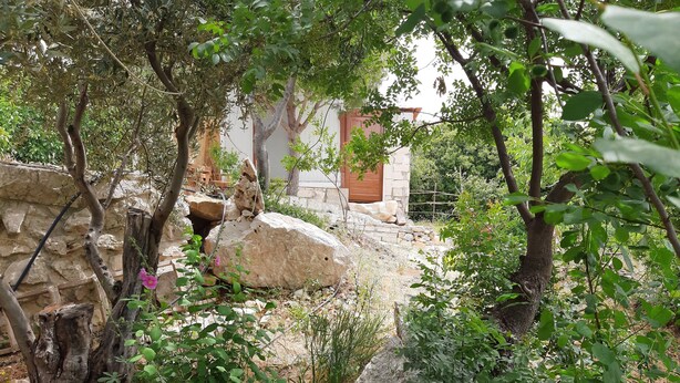 Un muro de piedra, una puerta de madera y un edificio de piedra en un jardín.