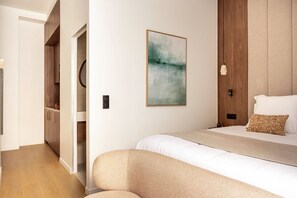 A hotel room with a bed, a bedside table, a wall-mounted painting, and a wooden wardrobe.