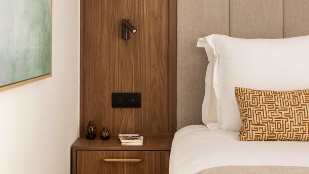 A bedroom with a wooden wardrobe, bedside table, and a bed with patterned pillows. - Studio luxe Paris 7 Lit King-Size Tour Eiffel (Paris)