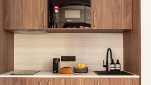 Una cocina con armarios de madera, microondas, cafetera, hogaza de pan, limones y tabla de cortar.