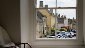 Une vue depuis une fenêtre donnant sur une rue bordée de voitures garées et de bâtiments traditionnels.