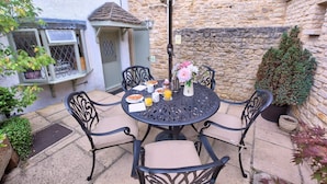 Une table ronde avec quatre chaises, un petit parasol et un vase avec des fleurs.