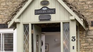 Une charmante maison ornée d’une lanterne, avec une façade en pierre, un petit porche et une enseigne portant le chiffre « 3 ».