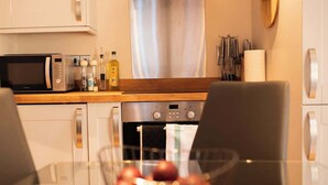 A modern kitchen with a microwave, oven, and various kitchen utensils on the counter. - Vineyard Style 2BR with Garden and Parking (Shudy Camps)