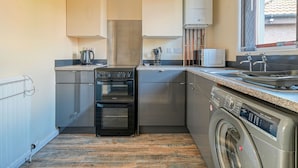 A compact kitchen with a stove, oven, microwave, and washing machine.